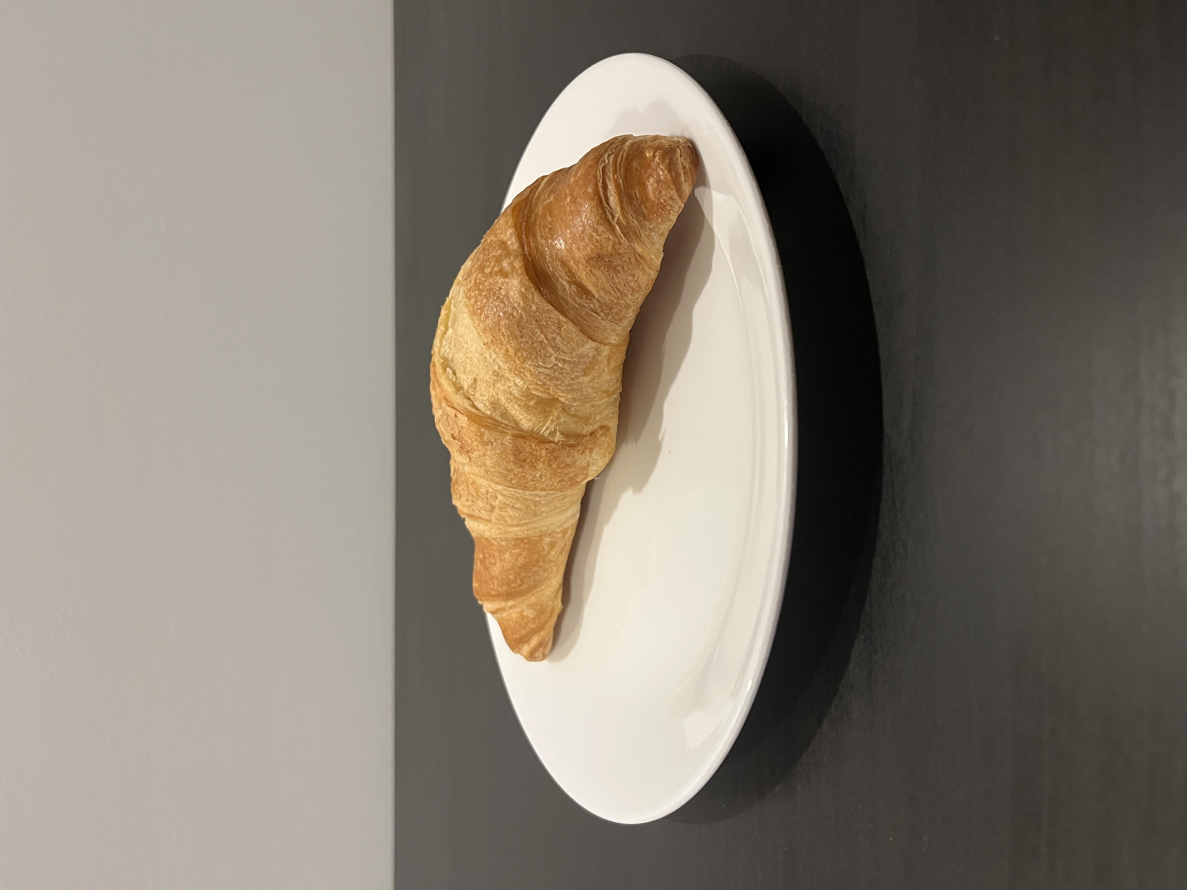 A croissant on a white plate.