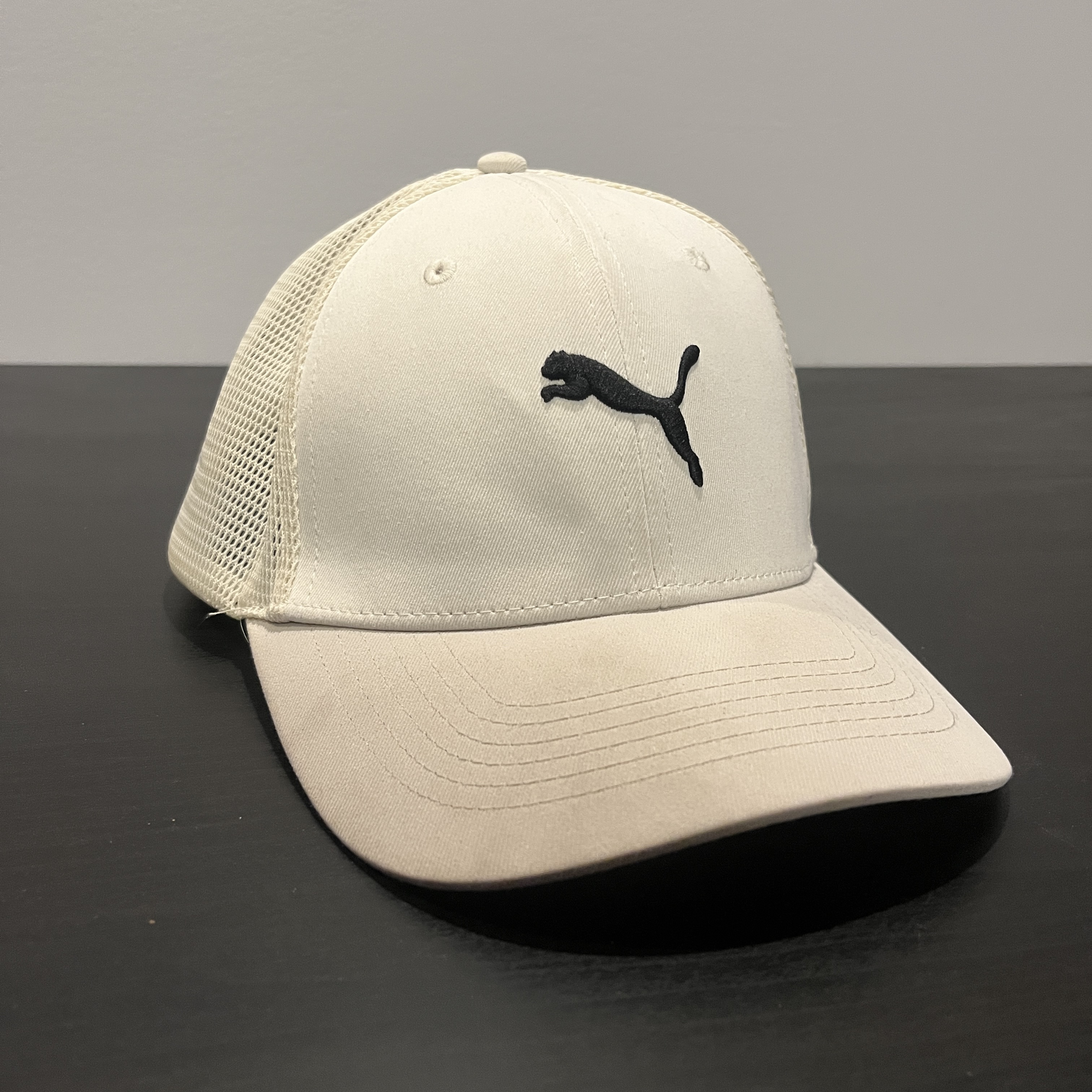 A white hat staged on a black table facing forwards right