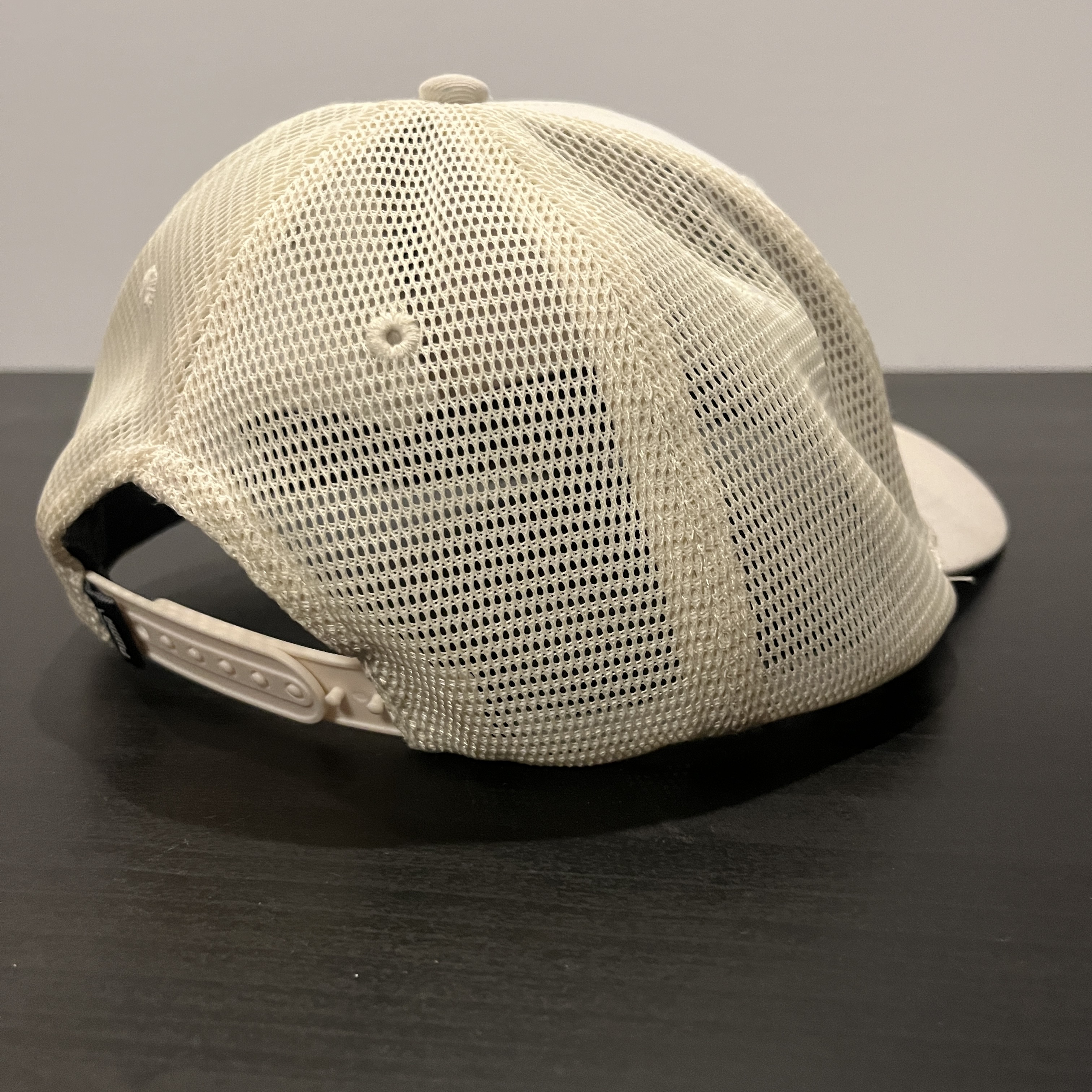 The Back of a white hat staged on a black table