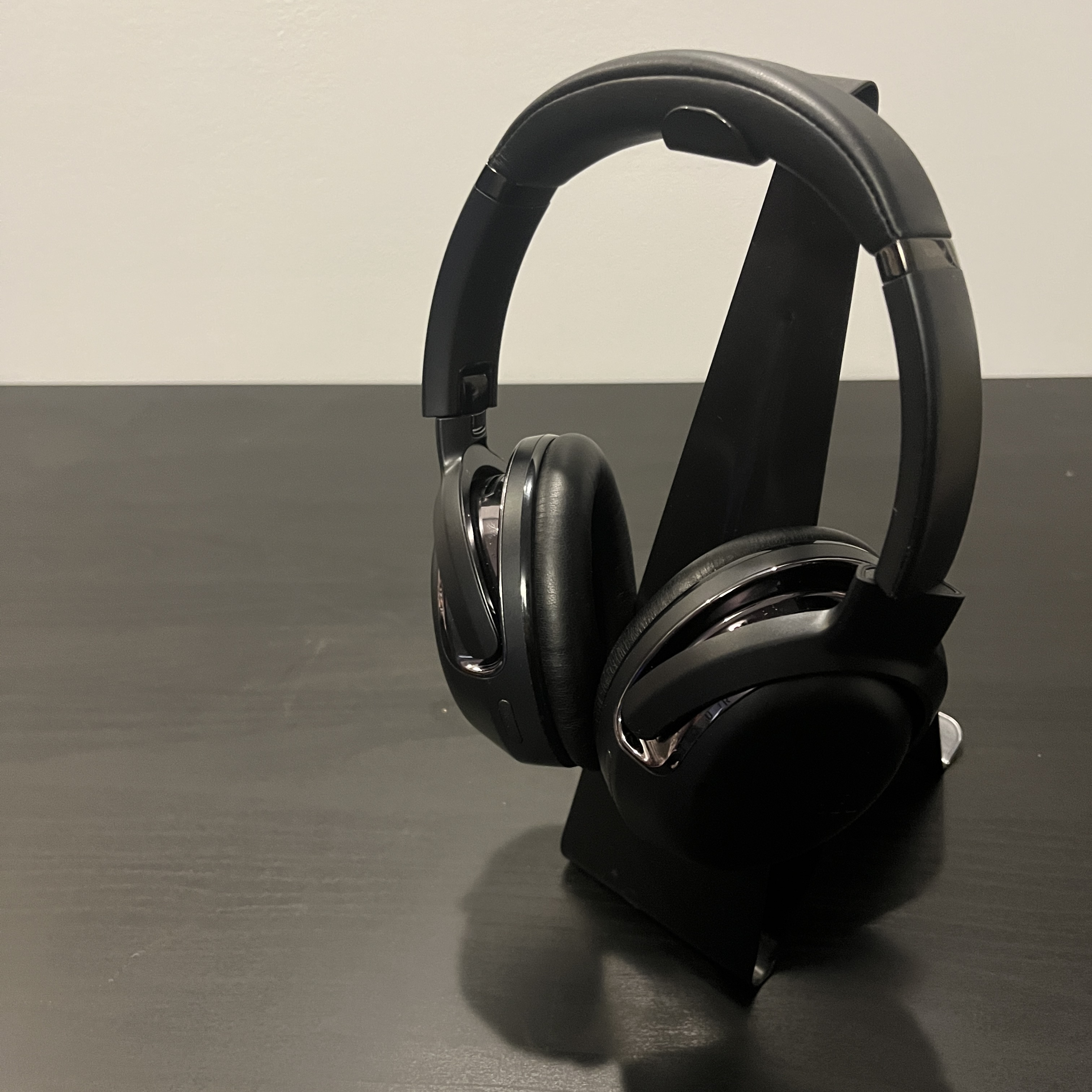 Black and silver over-ear headphones, staged on a balck table.