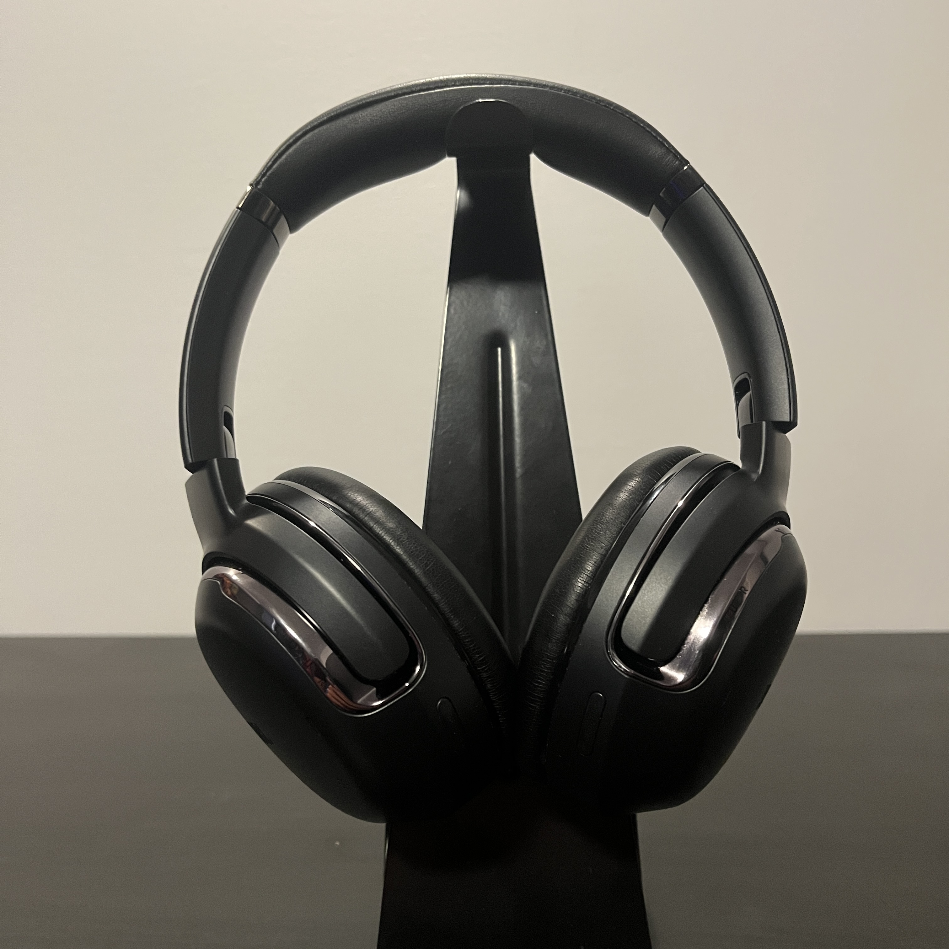 Black and silver over-ear headphones, staged on a balck table.